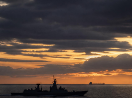 Pakistan’s Fleet Grew, But Its Seafarers Remain Unprotected A naval warship and a commercial cargo vessel navigating open ocean waters, representing maritime security and seafarer protection.
