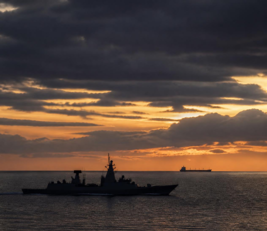 Pakistan’s Fleet Grew, But Its Seafarers Remain Unprotected A naval warship and a commercial cargo vessel navigating open ocean waters, representing maritime security and seafarer protection.